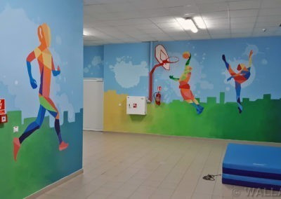 Pomalowane ściany - MOSiR Mokotów - łącznik szkoły i basenu. Kolorowe postacie sportowe i dynamiczne kolorowe tło tworzą ciekawy mural w korytarzu szkoły.