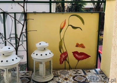 Malowidło na balkonie. Mały mural, grafika iluzjonistyczna przedstawiająca twarz kobiety z kwiatów i motyla - daje to ciekawe złudzenie optyczne.
