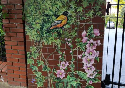 pomalowany murek - mural na cegłach przedstawiający motywy roślinne oraz ptaki
